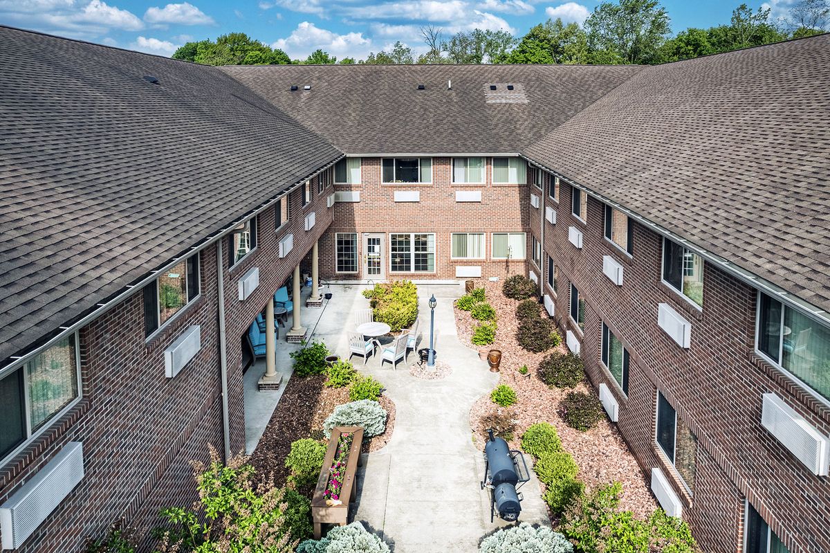 Aerial view of a courtyard in a brick apartment complex, featuring landscaped gardens and outdoor seating.
