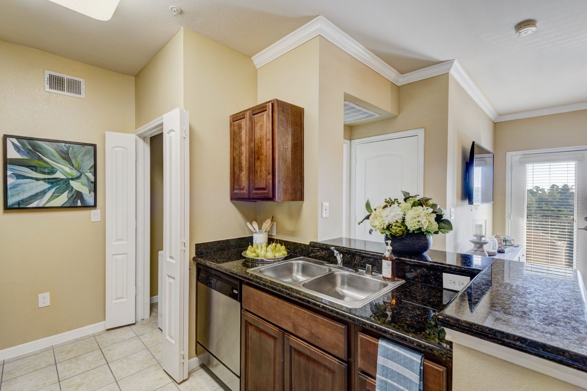 A modern kitchen with dark countertops, wooden cabinets, and a decorative flower arrangement.