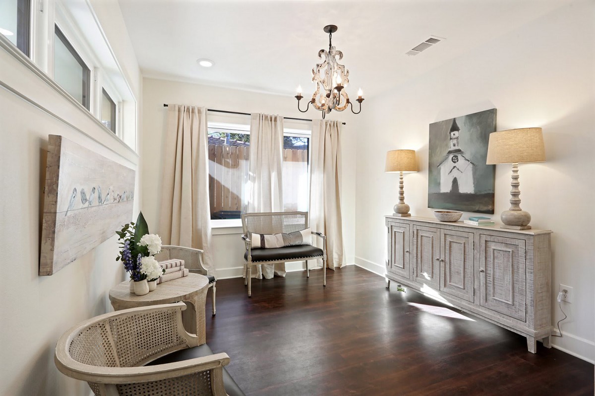 A cozy living room with elegant decor, featuring a chandelier, hardwood floors, and soft lighting.
