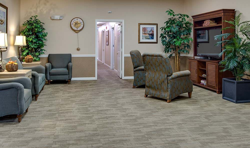 A cozy waiting room with armchairs, a clock, and decorative elements leading to a hallway.