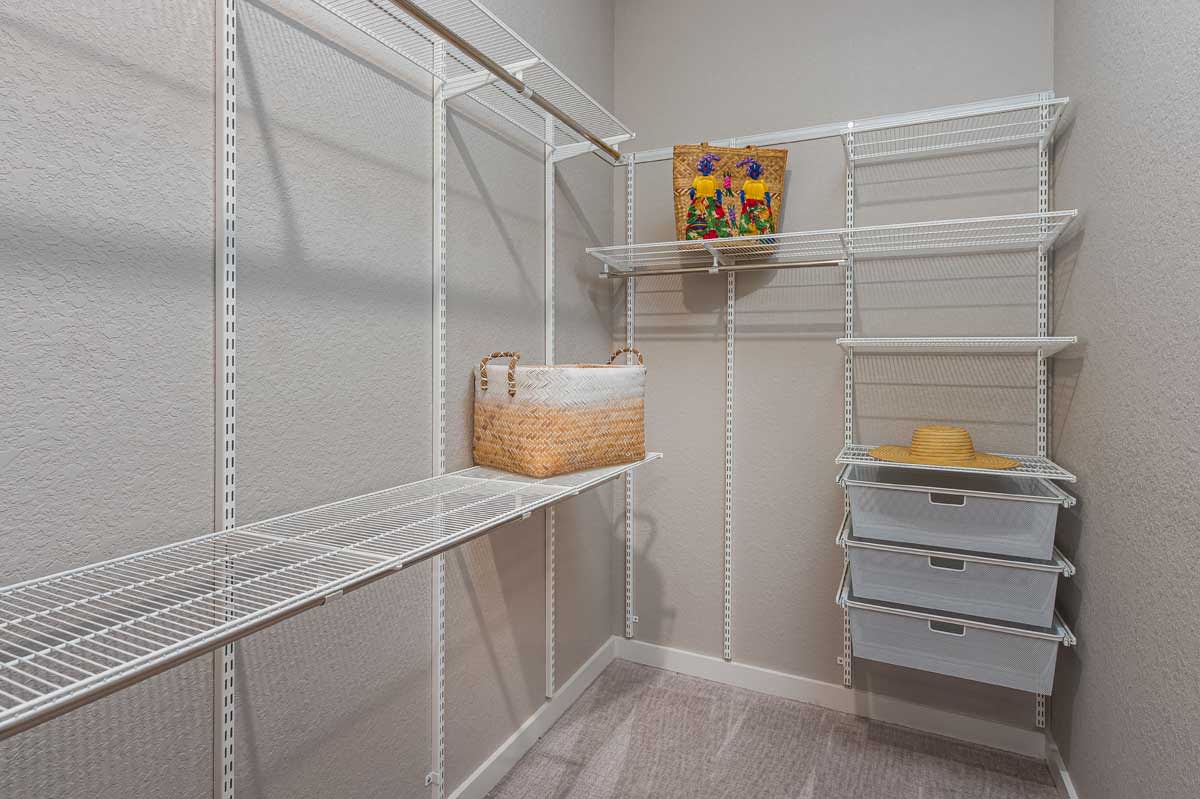 An organized closet with white wire shelving for storage.