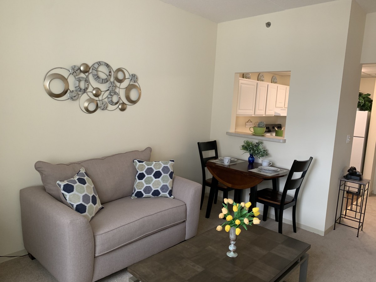 A cozy living room with a stylish sofa and decorative wall art, featuring a small dining area.