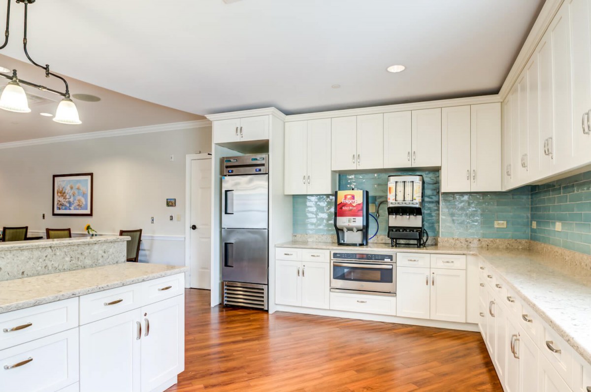 A modern kitchen with white cabinets, sleek appliances, and hardwood flooring.