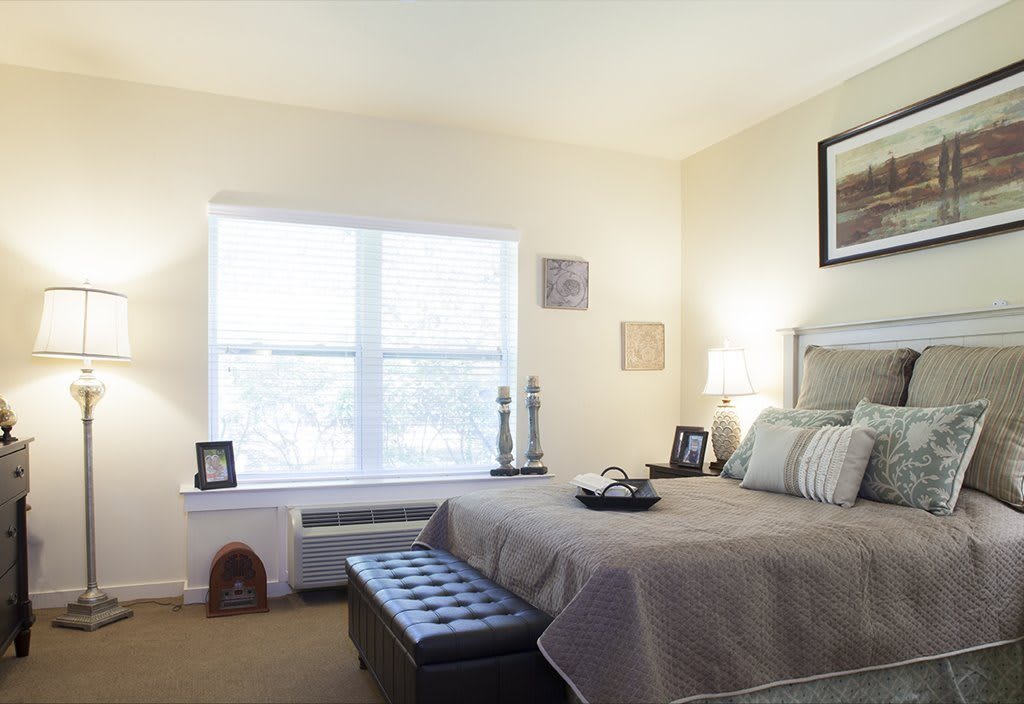 A well-lit bedroom with a neatly made bed and tasteful decor.