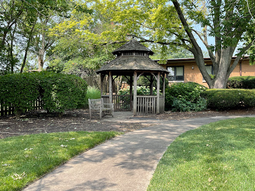 A serene gazebo surrounded by lush greenery and a winding pathway, inviting visitors to relax and enjoy the outdoors.