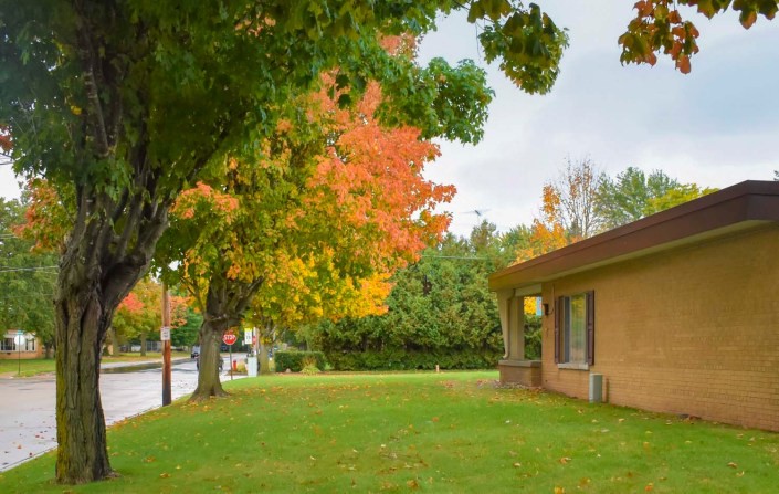 A suburban house surrounded by trees with vibrant autumn leaves.
