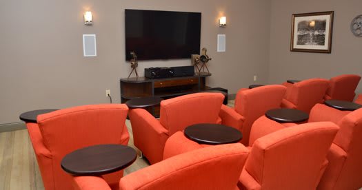 A cozy home theater room with orange seating and a large TV screen.
