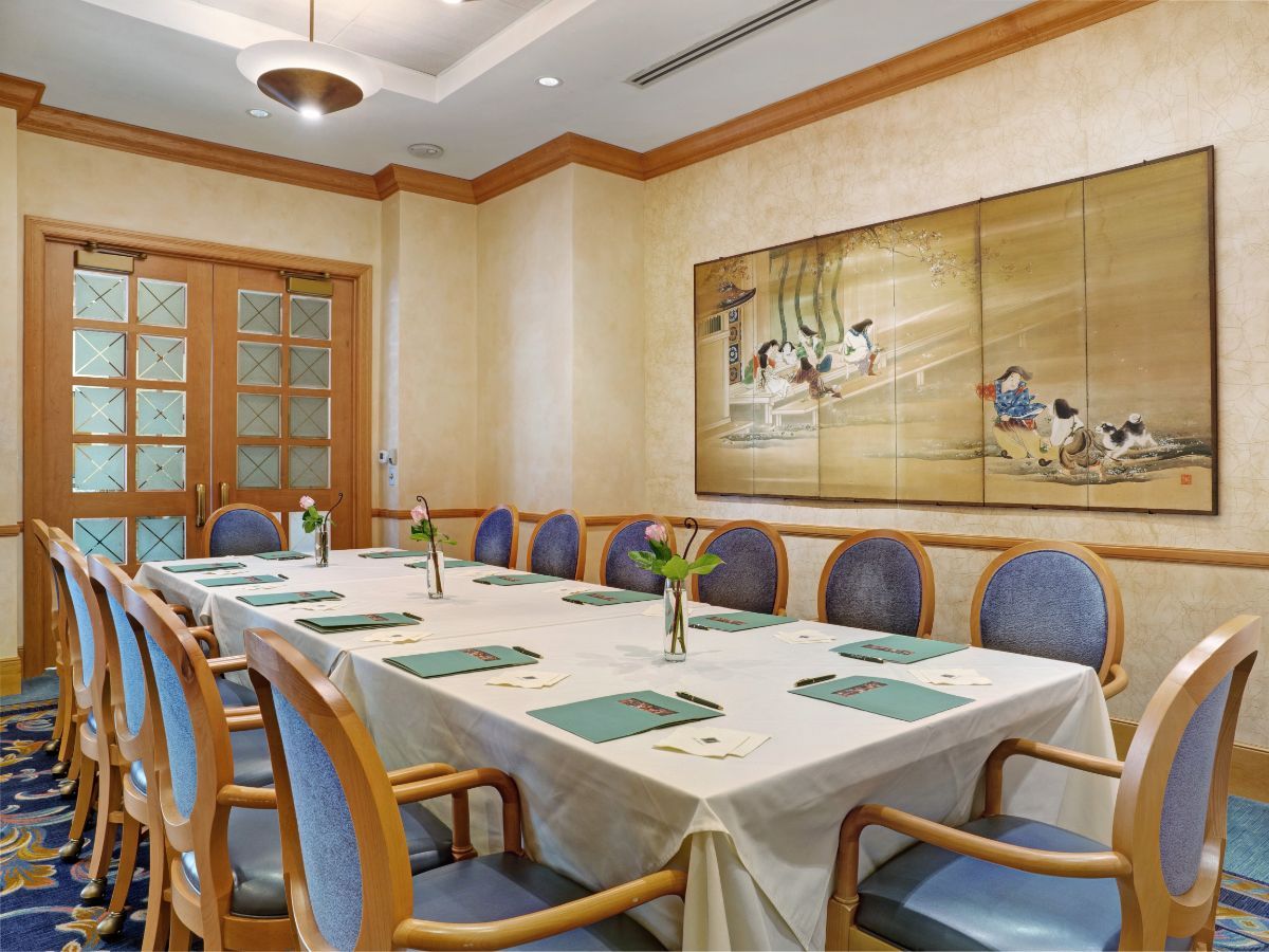 A well-appointed meeting room with a large table and chairs, adorned with elegant artwork on the wall.