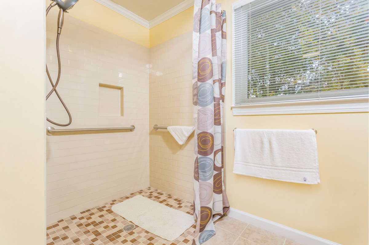 A bright bathroom with a shower area, featuring a patterned shower curtain and tiled floor.