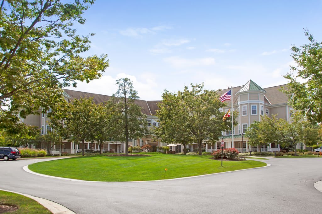 A residential building with a circular driveway surrounded by trees and a well-maintained lawn.