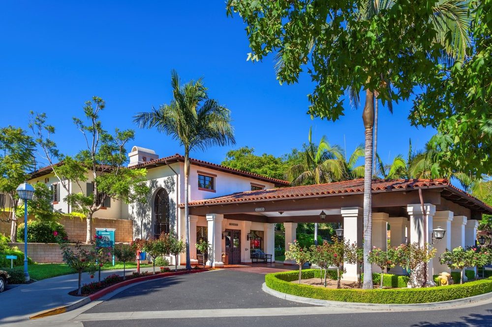 A luxurious resort entrance surrounded by palm trees and lush landscaping.