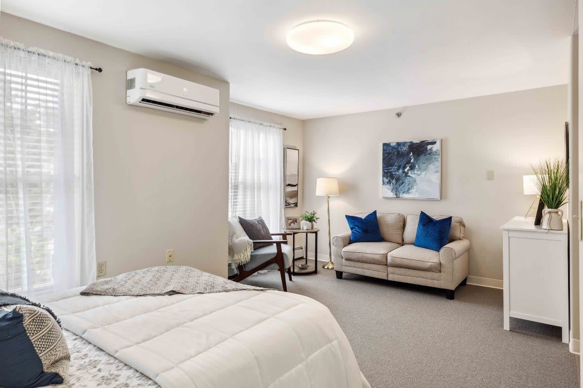 A cozy bedroom featuring a comfortable bed, modern sofa with blue cushions, and stylish decor.