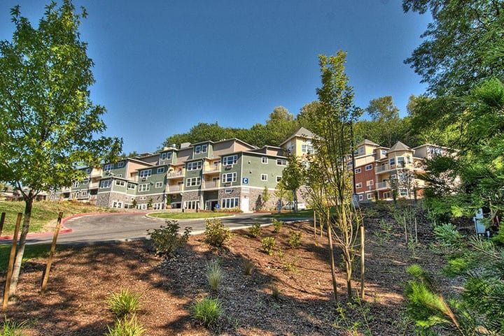 A scenic view of residential apartment buildings surrounded by greenery and a clear blue sky.
