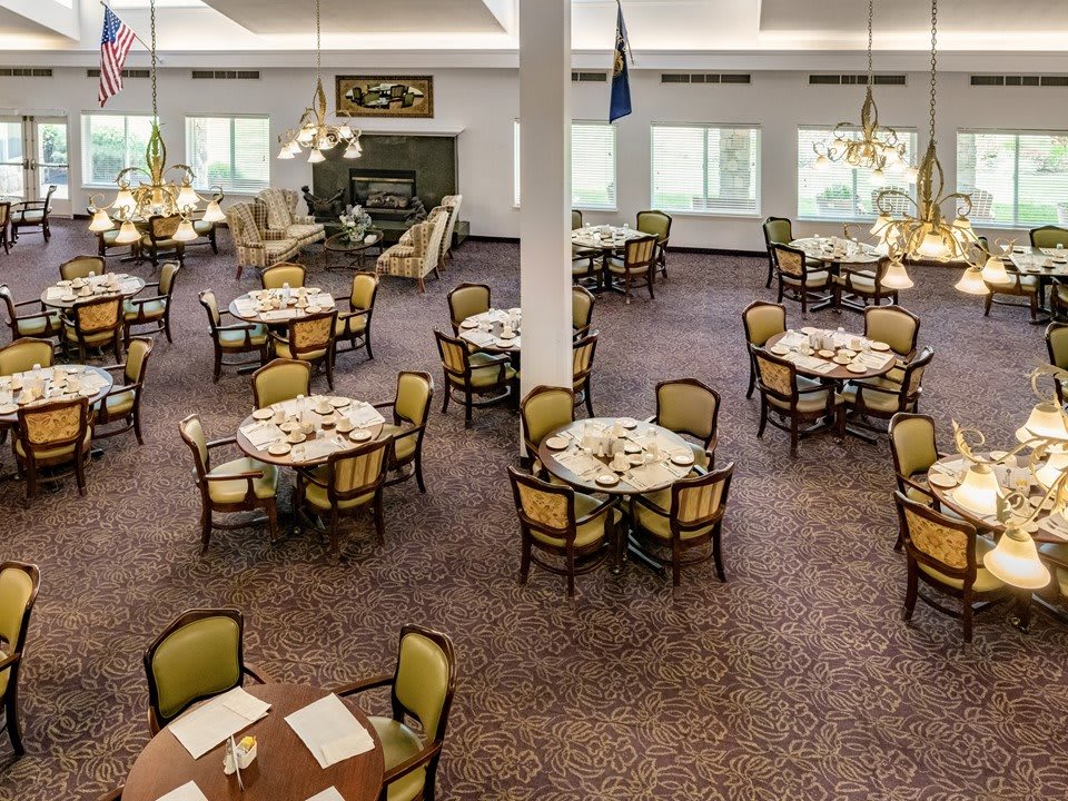 A spacious dining area with neatly arranged tables and chairs on a carpeted floor.
