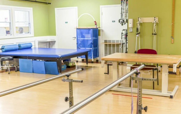 A physical therapy room equipped with exercise tables and parallel bars.