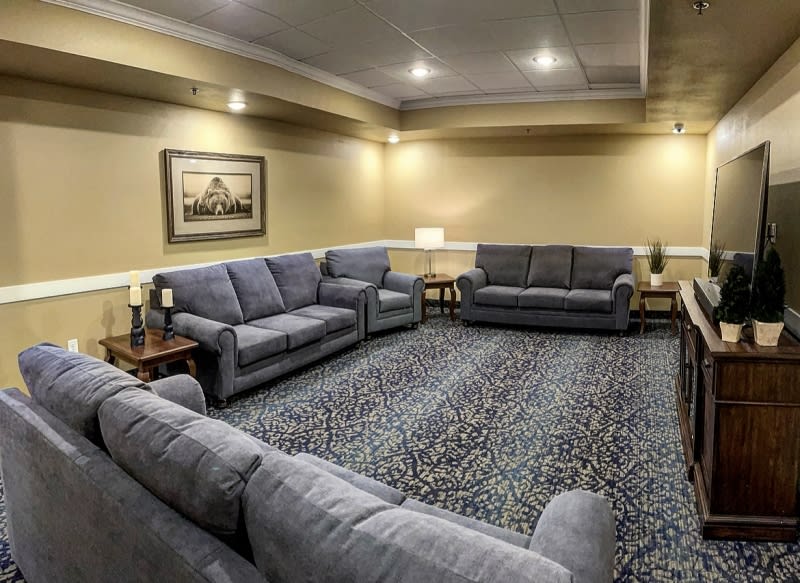 A cozy and well-furnished living room with multiple sofas arranged around a large carpet.