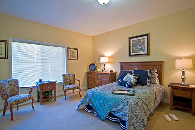 A cozy and well-decorated bedroom with a comfortable bed, bedside table, and a window allowing natural light.