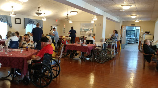A bustling dining area in a nursing home with residents and caregivers engaging in activity.