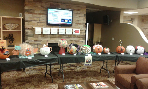 An array of creatively decorated pumpkins displayed on tables, showcasing artistic talent at a community event.
