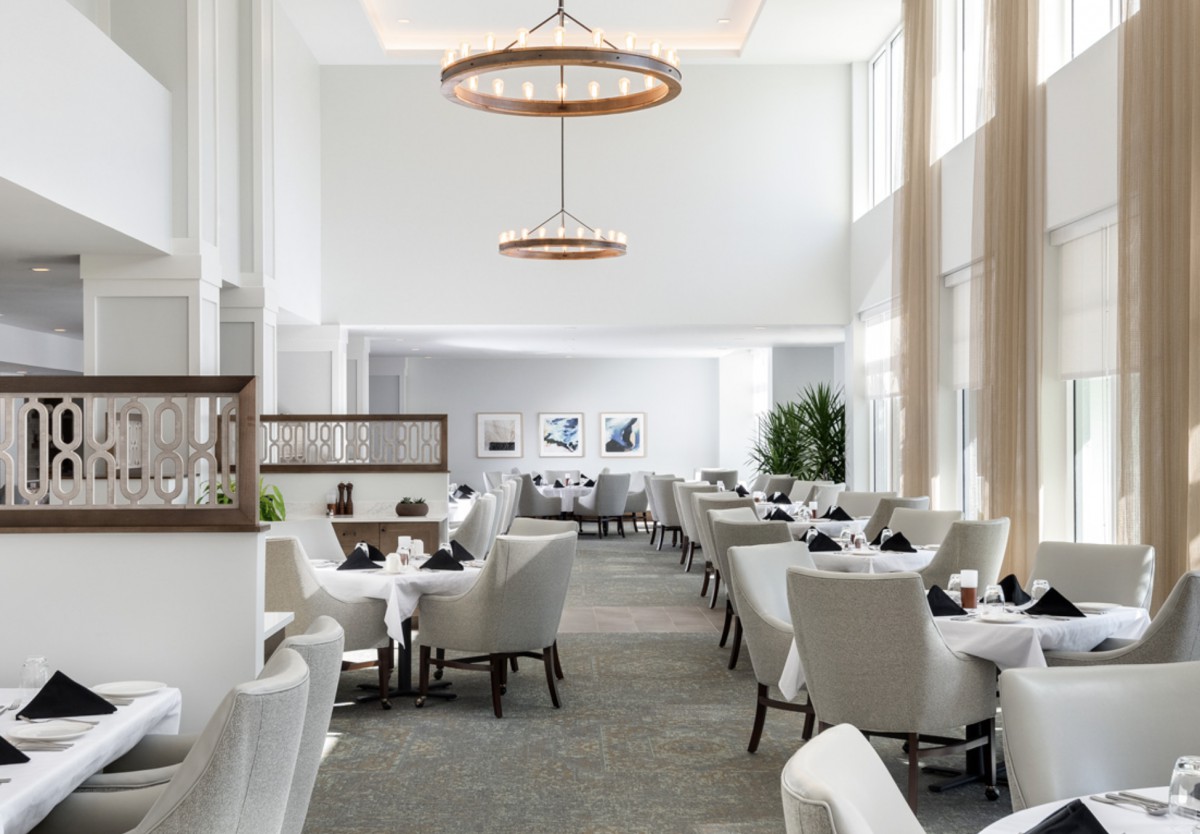 A spacious and modern restaurant interior with elegant chandeliers and comfortable seating.