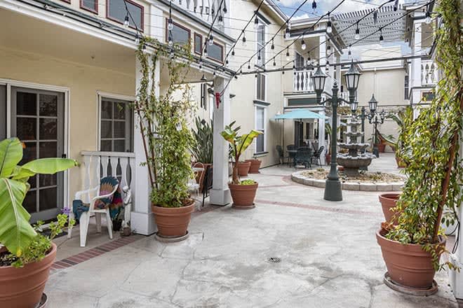 A charming courtyard with a central fountain, surrounded by potted plants and outdoor seating.