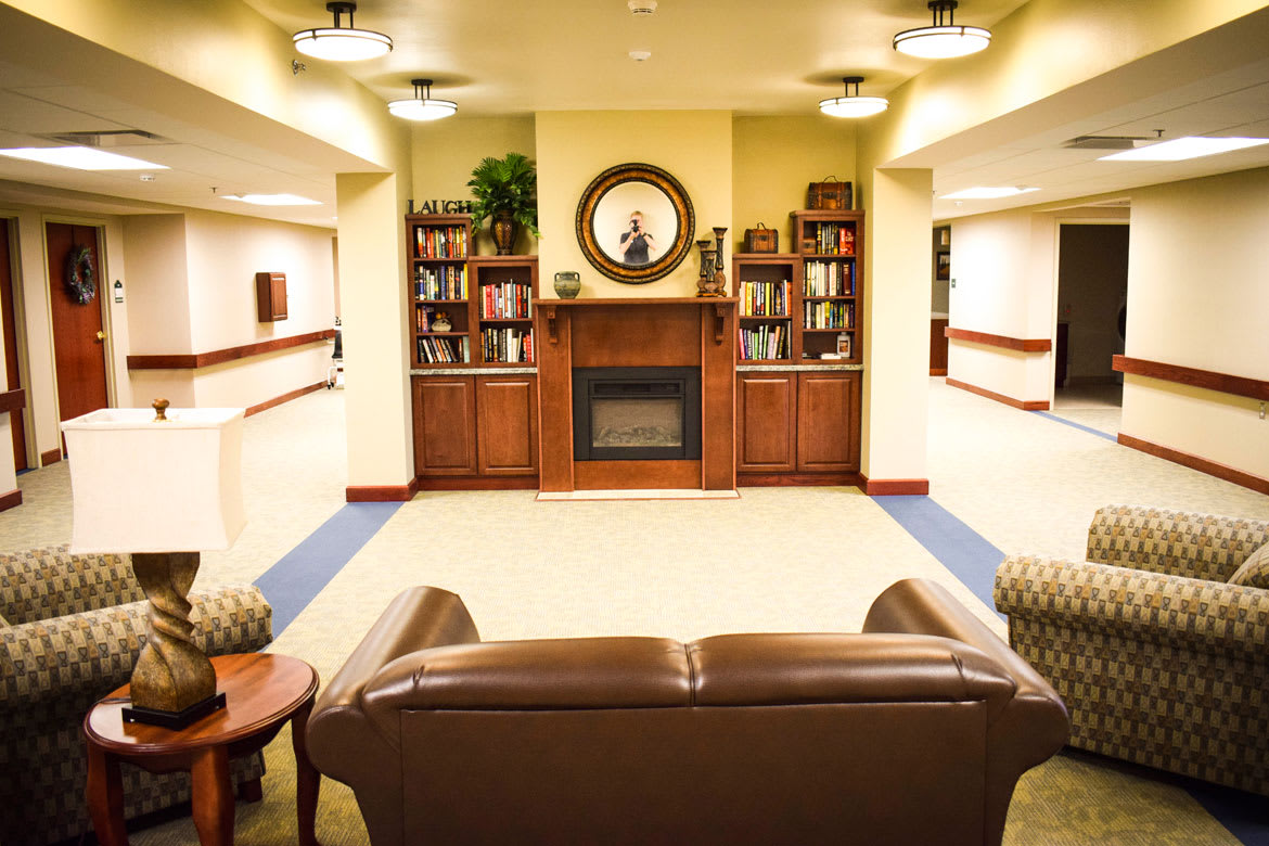 A cozy living room featuring a fireplace and bookshelves, with comfortable seating arrangements.