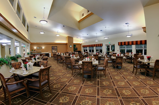 A spacious dining area set up with neatly arranged tables and chairs, illuminated by soft lighting.