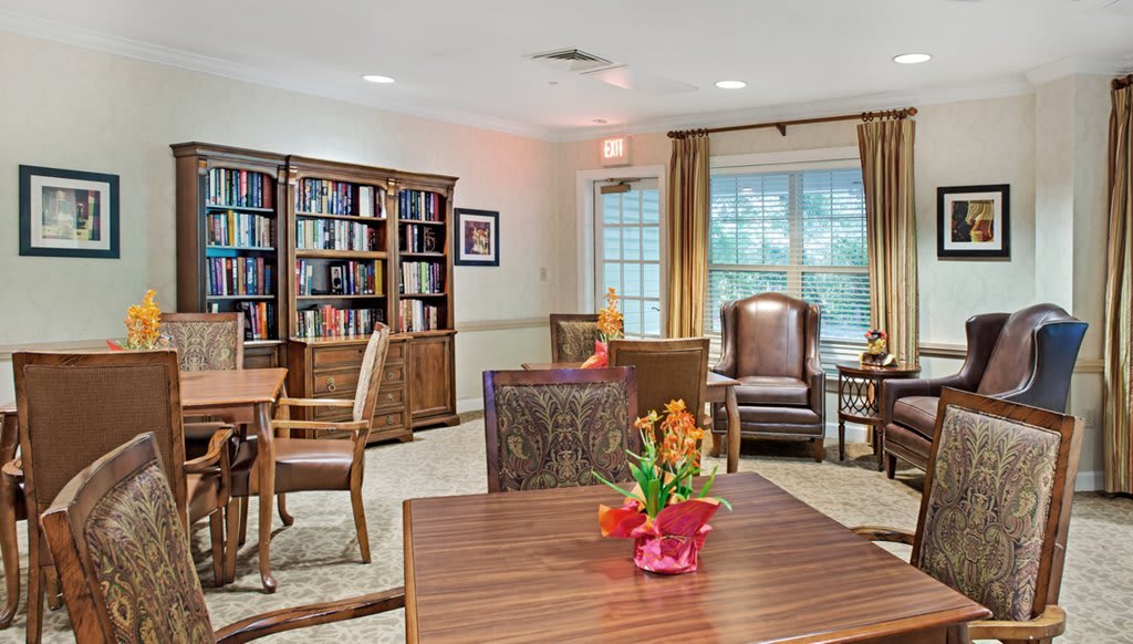 A cozy reading room with bookshelves, tables, and chairs.