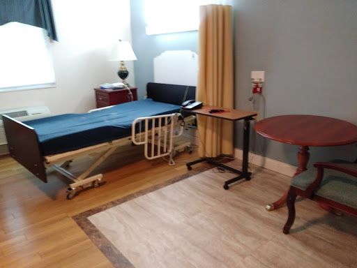 A simple and clean hospital room featuring a bed, a nightstand, and a small table.