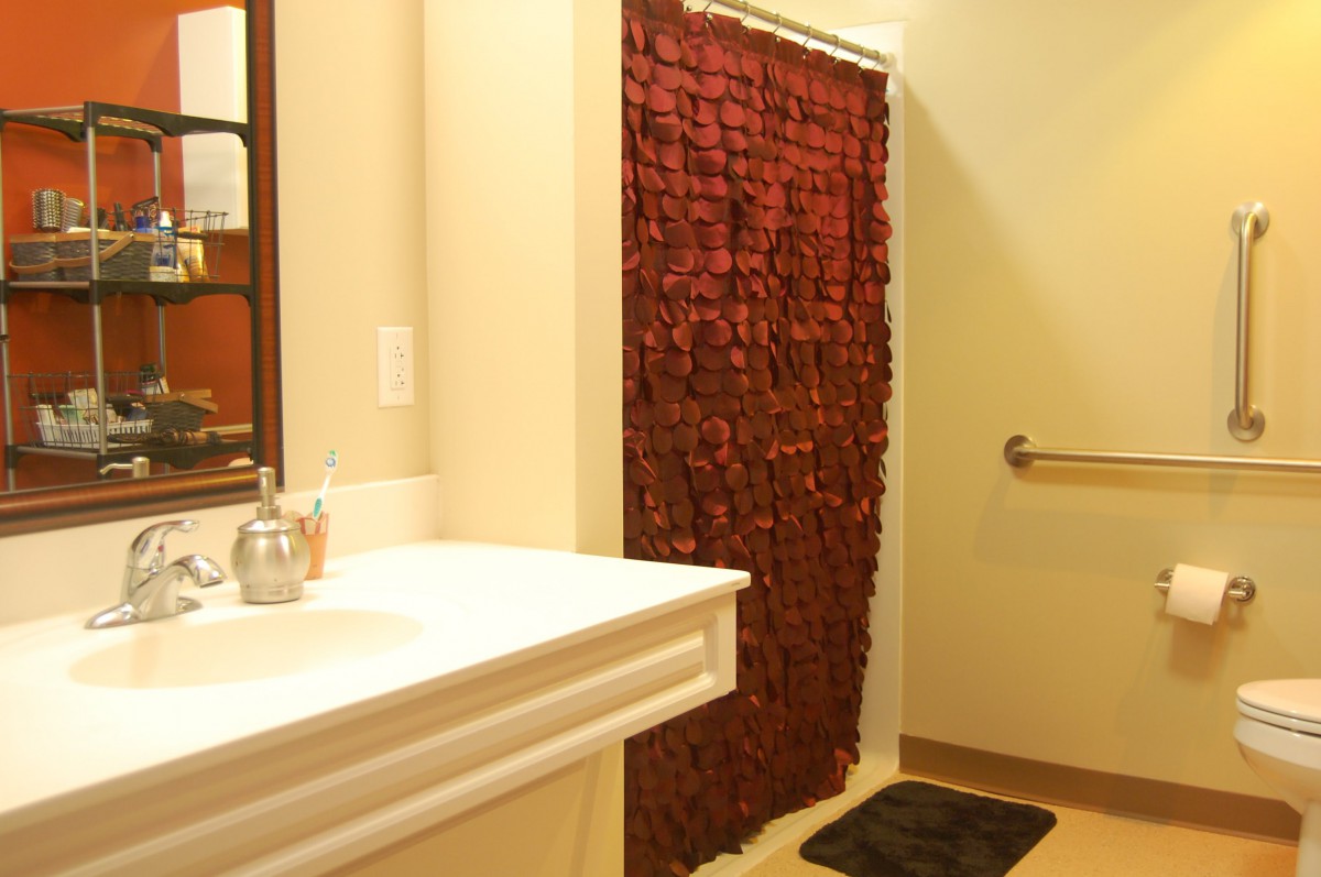 A bathroom featuring a red shower curtain and a white sink with a mirror.