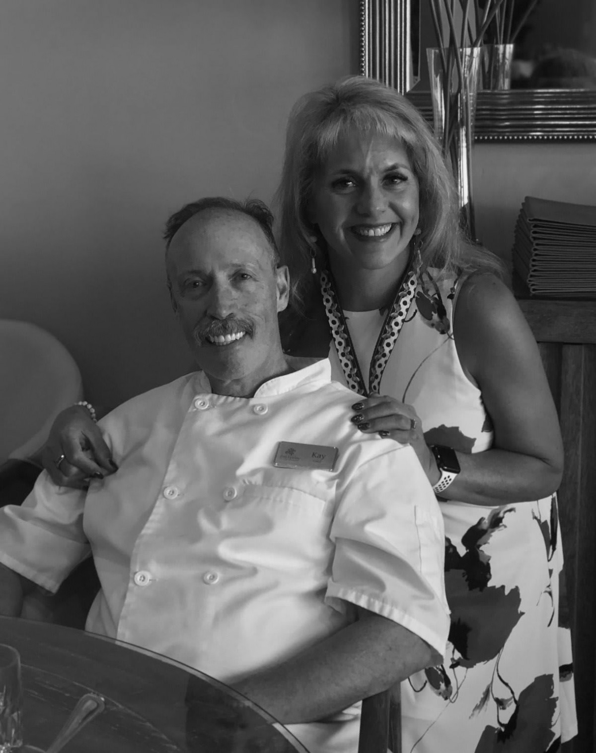 A smiling couple posed indoors in a black and white photo.