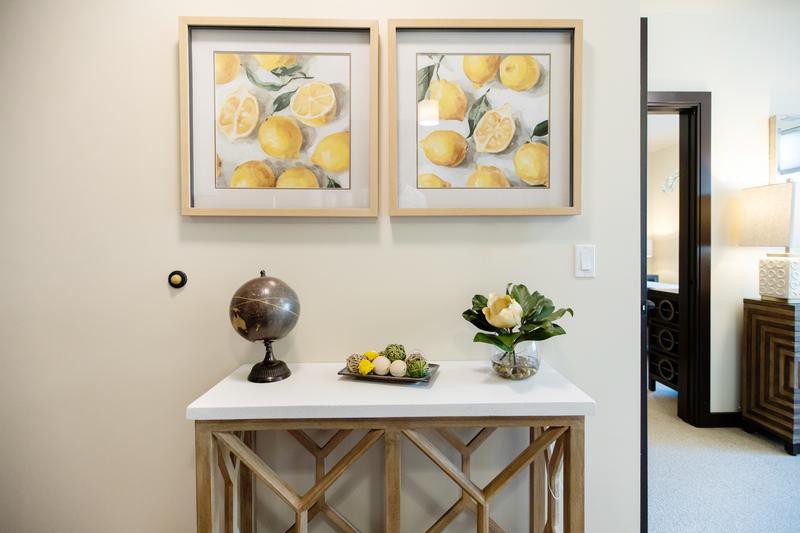 A stylish console table decorated with lemon-themed artwork, a globe, and fresh flowers.