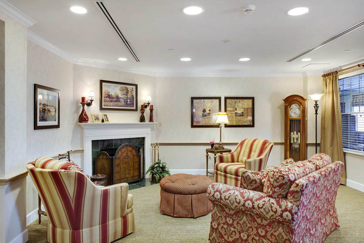 A cozy living room featuring armchairs, a fireplace, and artwork on the walls.