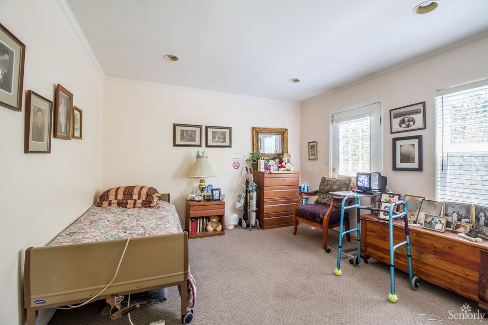 A cozy bedroom with a hospital bed and a walker, featuring homey decor and furniture.