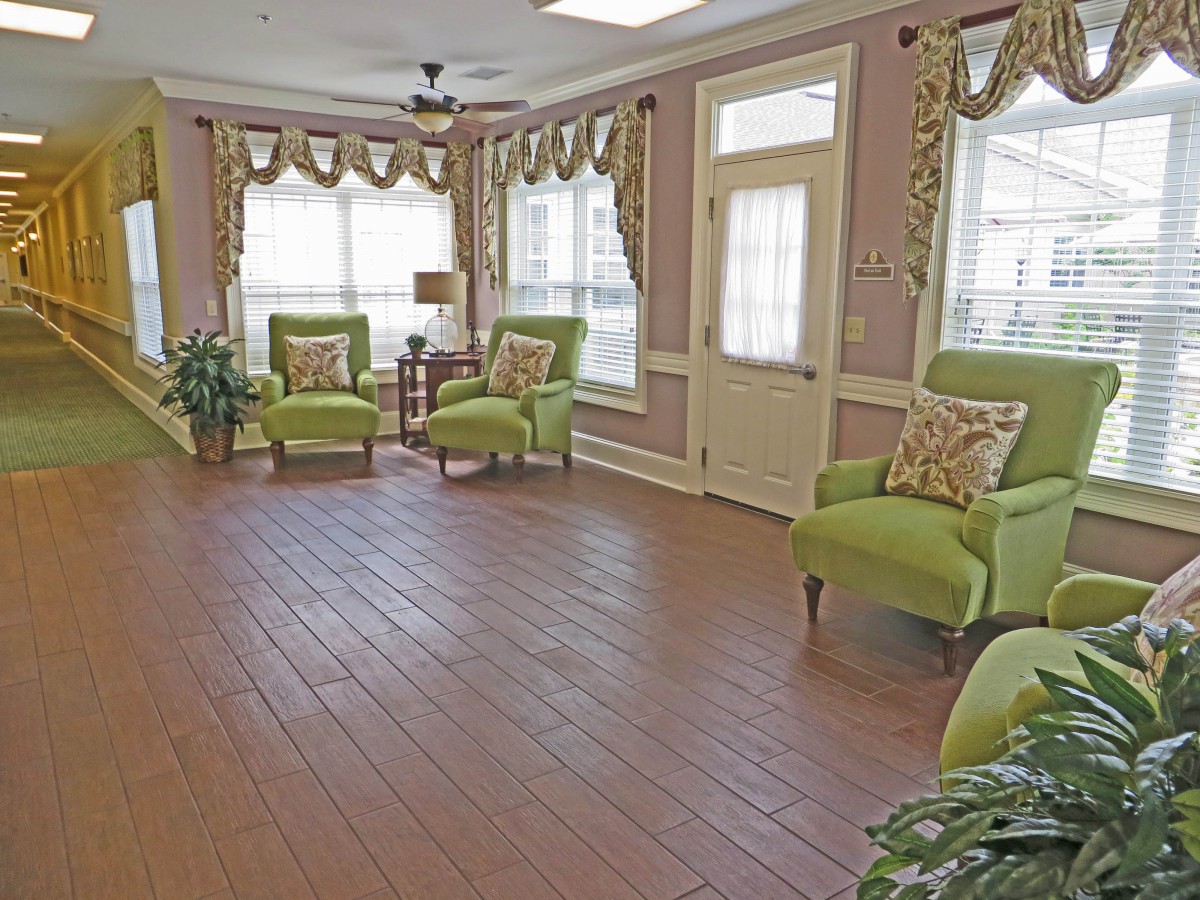 A bright living room with green chairs and large windows.