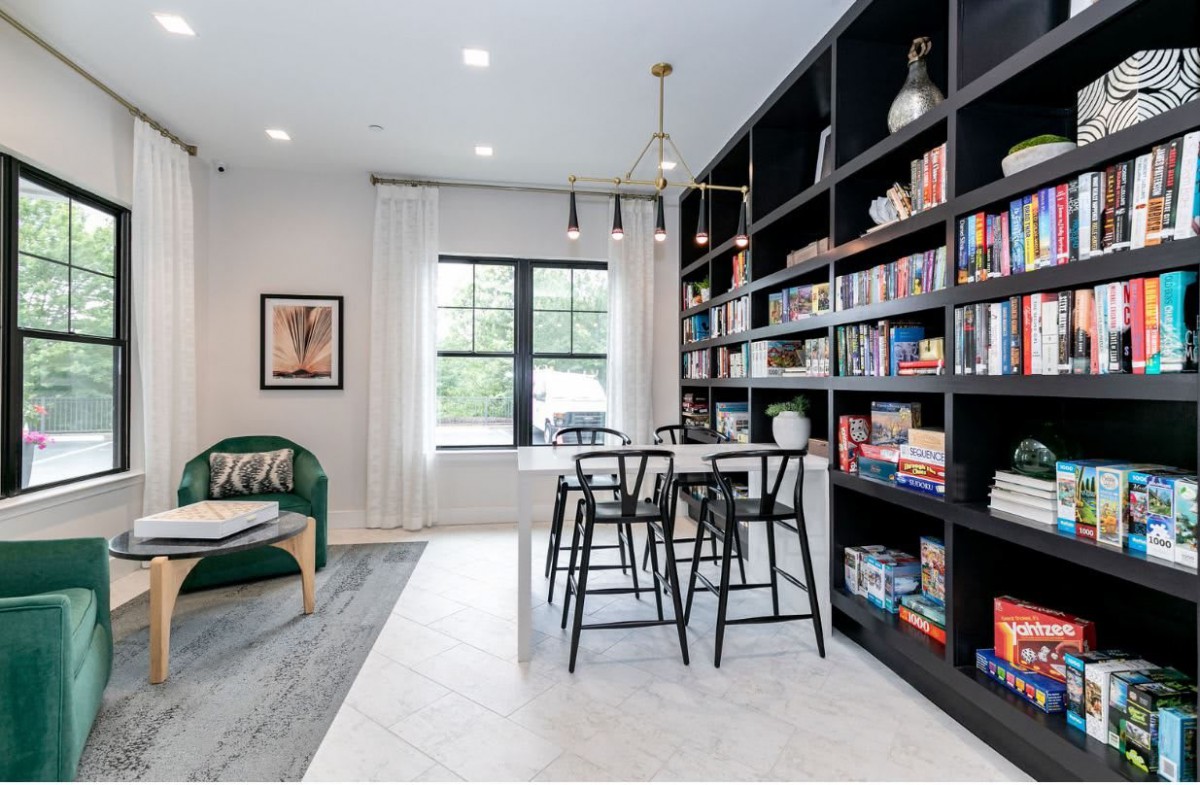 A modern living room with a large bookshelf and a seating area, featuring stylish furniture and decor.