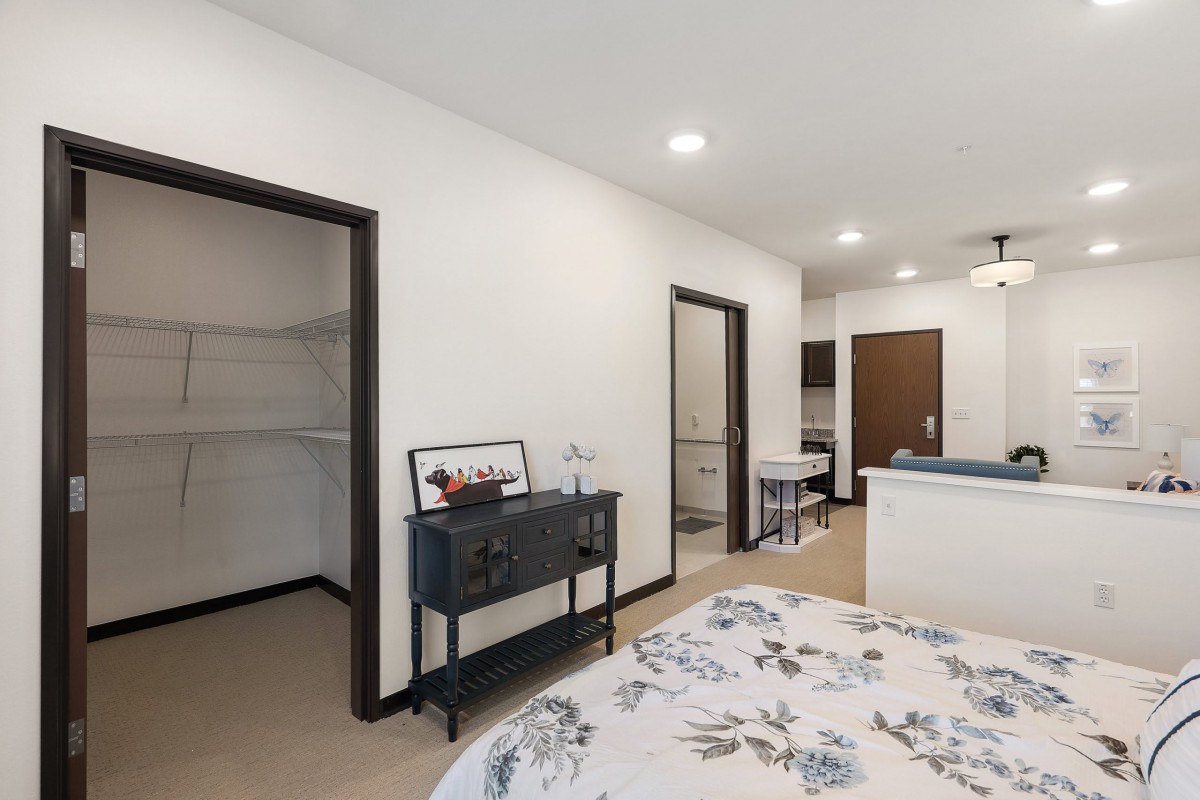 A modern bedroom with a walk-in closet and floral bedding, featuring minimalistic decor.