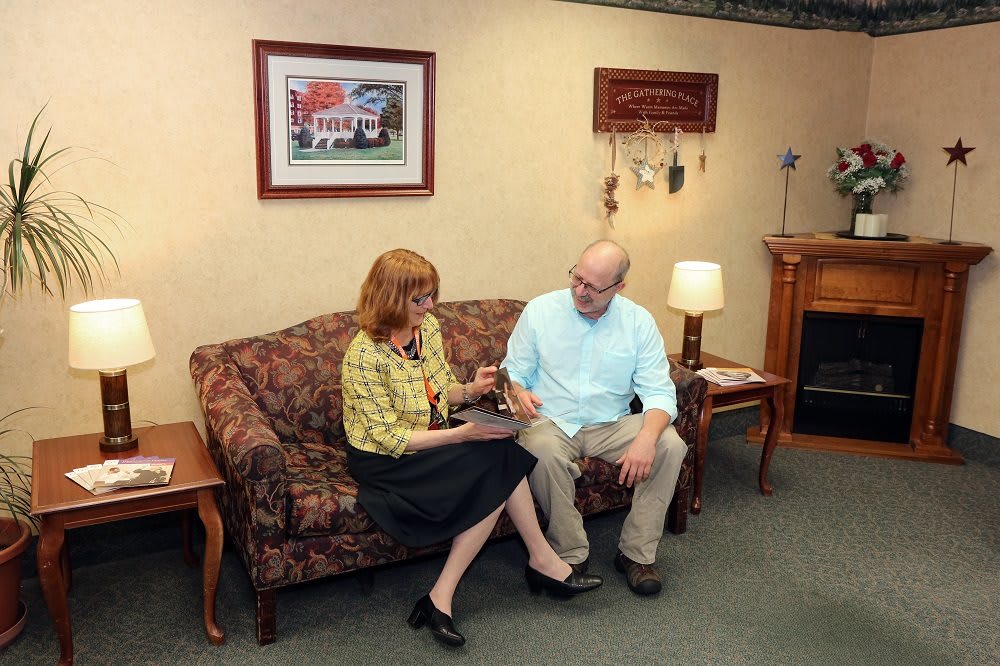 Two people sitting on a couch having a conversation in a living room setting.