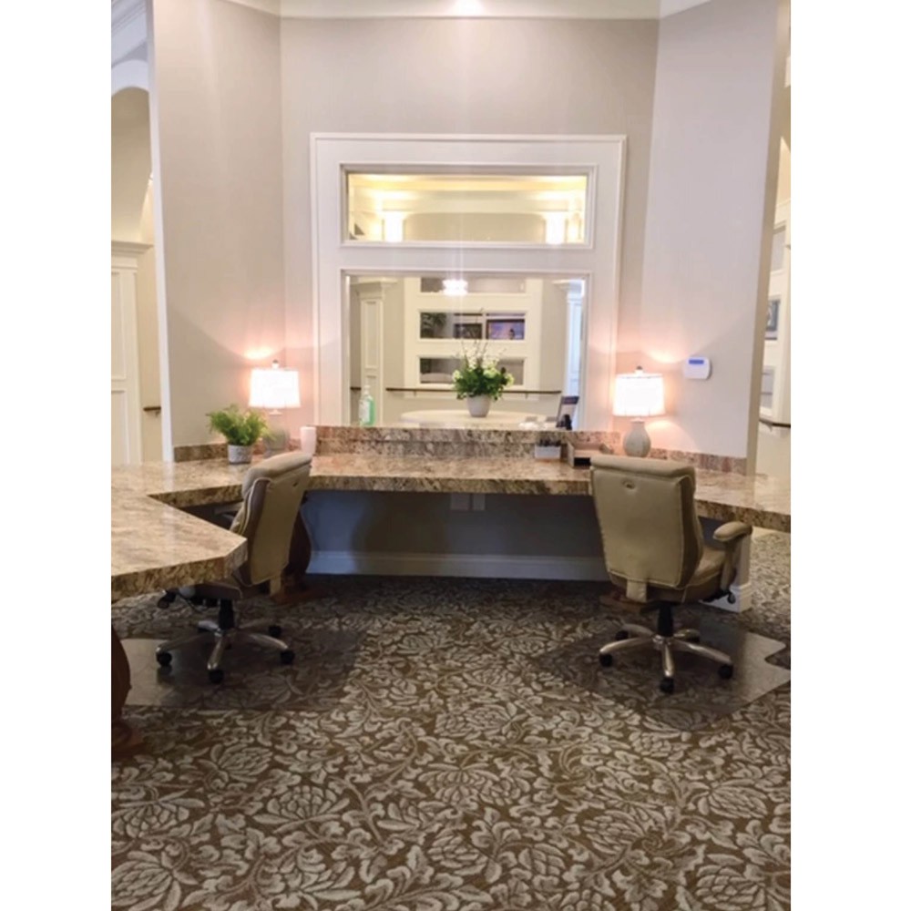 A modern office workspace featuring two desks with chairs, stylish lamps, and a patterned carpet.