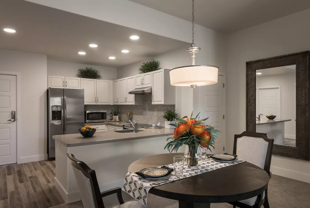 A modern kitchen with sleek stainless steel appliances and a cozy dining area featuring a stylish pendant light.