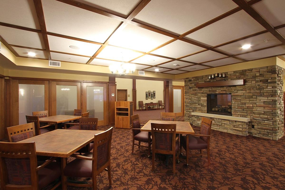 A cozy dining room featuring wooden tables and chairs, with a stone fireplace and unique ceiling design.