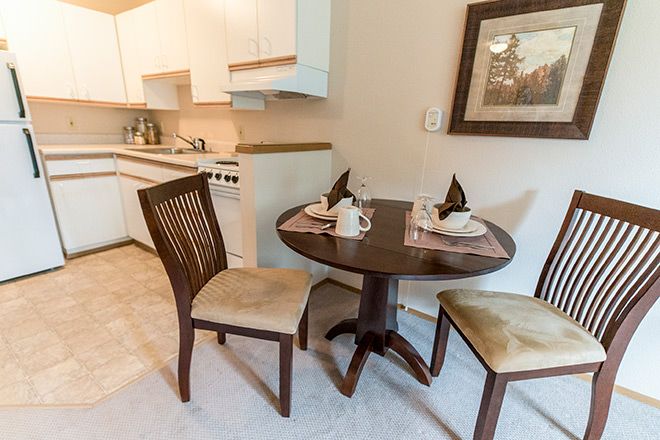 A cozy dining area with a small round table set for two in a kitchen space.
