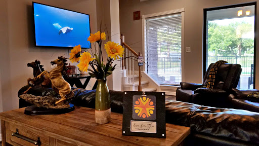 A cozy living room setup featuring a vase of yellow flowers and a decorative piece on a wooden table, with a television in the background.