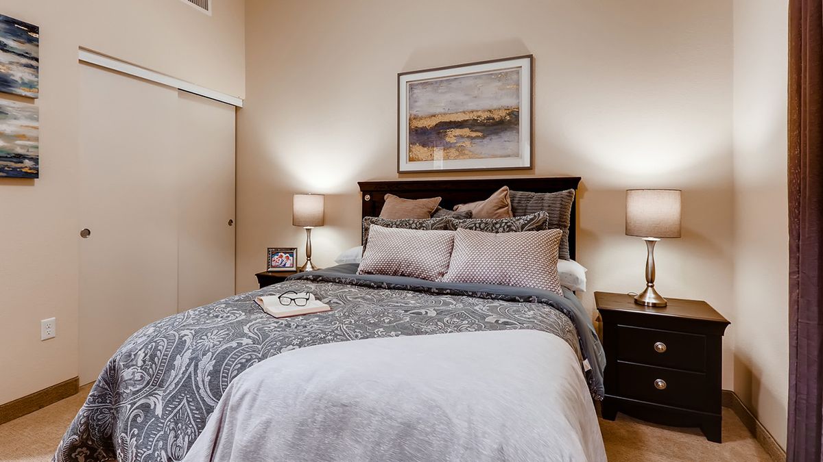 A cozy and modern bedroom with stylish decor, featuring a comfortable bed, soft lighting from lamps, and inviting bedding.