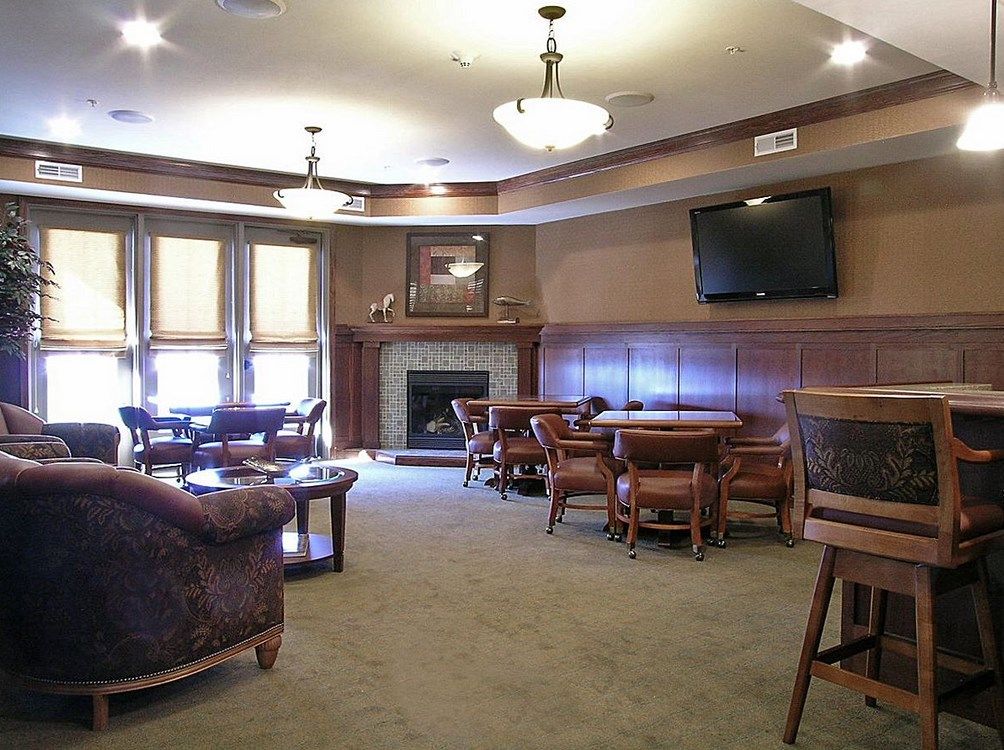 A cozy lounge area featuring comfortable seating, a fireplace, and a mounted television.