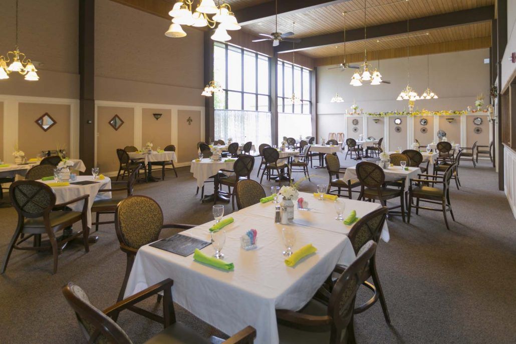 Spacious dining room with neatly set tables and large windows.