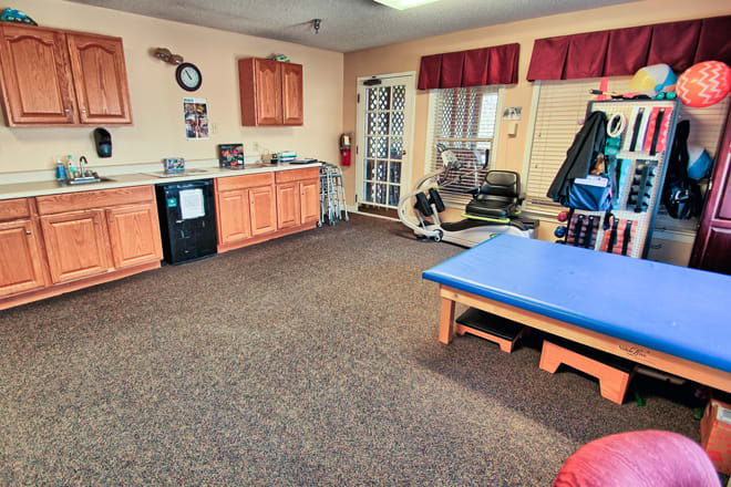 A well-equipped physical therapy room with various exercise equipment and a treatment table.
