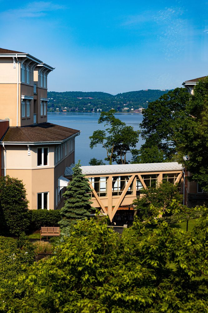 Scenic view of buildings and a bridge overlooking a tranquil lake surrounded by trees.