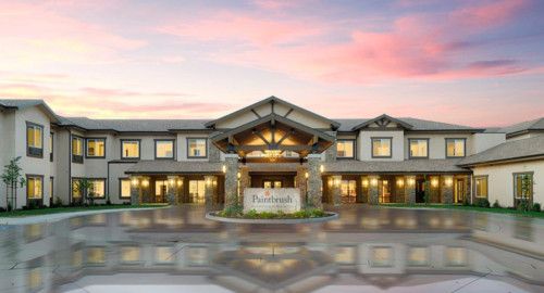 Front view of a building entrance at sunset with illuminated lights.