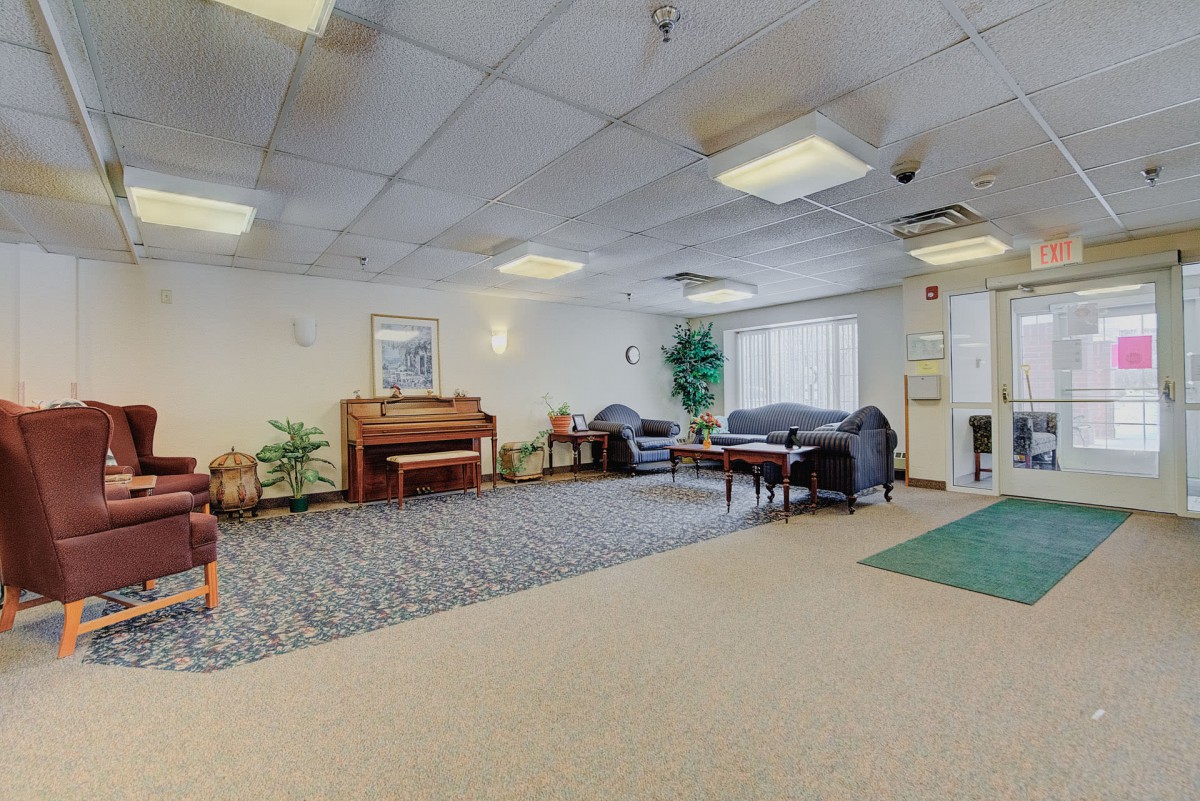 A spacious lobby with a piano, seating area, and indoor plants.